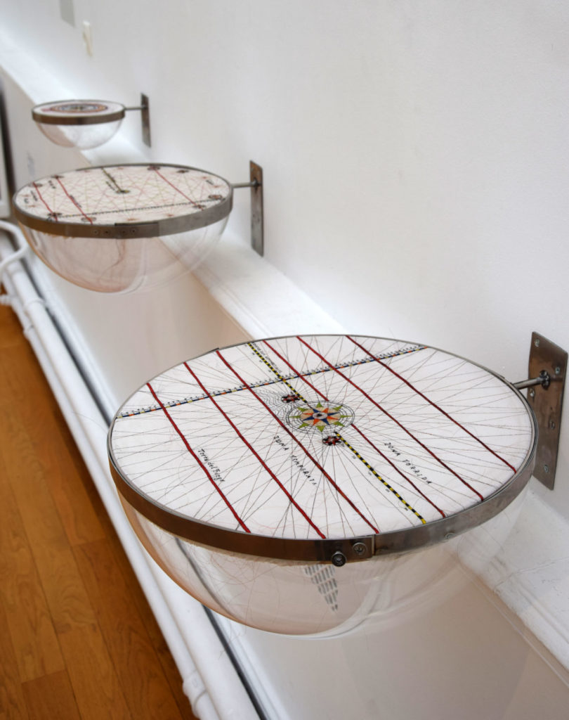 Vue de la série Portulans. En premier plan Portulans III, Terra del fuego, 2021 – 2024, broderie en cheveux naturels et colorés sur soie, support en plexiglas, inox, 25